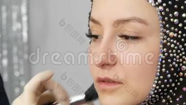 化妆底座应用于模特特写的面部.. 年轻女孩模特在工作室里有一双漂亮的棕色眼睛